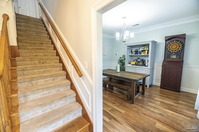 5013 Roland Rd, Pace, FL 32571 - staircase featuring a chandelier, wood finished floors, ornamental molding, and wainscoting