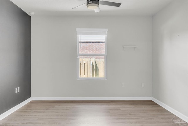 empty room with ceiling fan, light wood-style floors, and baseboards