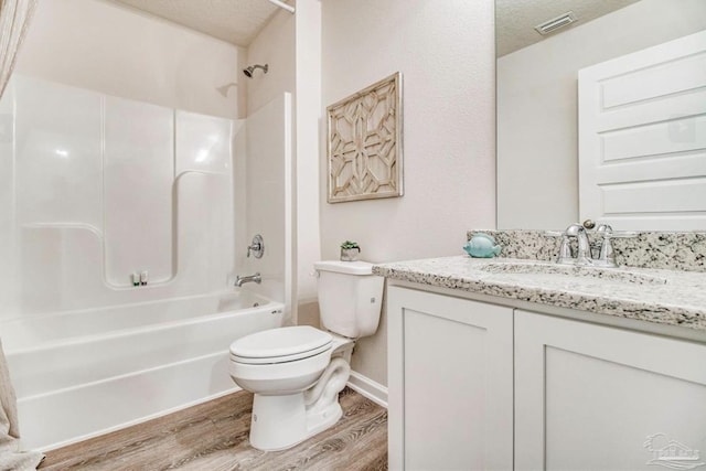 bathroom with vanity, toilet, visible vents, bathtub / shower combination, and wood finished floors