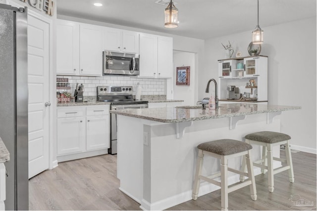 kitchen featuring stainless steel appliances, tasteful backsplash, light wood-type flooring, and white cabinetry