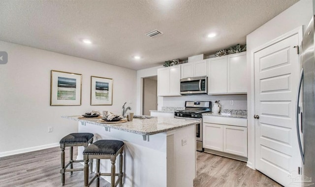 kitchen with light wood-style flooring, a kitchen bar, visible vents, a sink, and stainless steel appliances