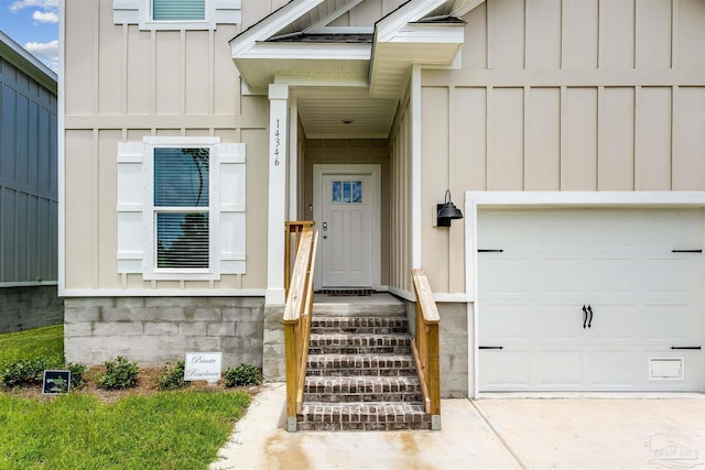 view of exterior entry featuring board and batten siding, concrete driveway, and a garage