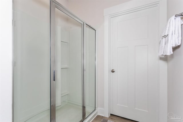 full bathroom with a stall shower and wood finished floors