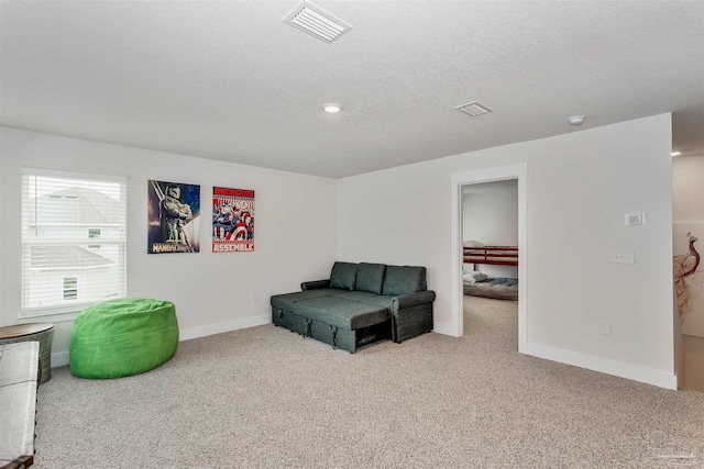 sitting room with baseboards, visible vents, a textured ceiling, and light colored carpet