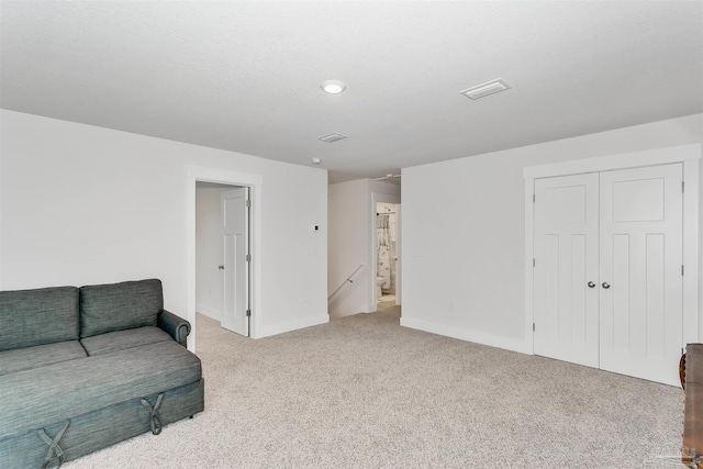 living area with baseboards, visible vents, light colored carpet, and an upstairs landing