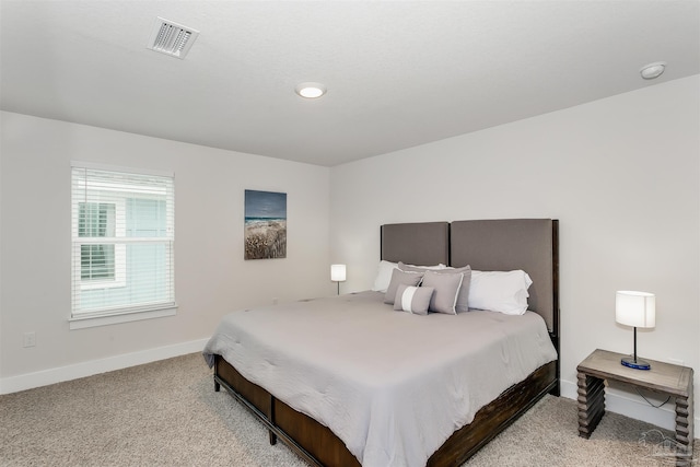 bedroom with visible vents, light carpet, and baseboards