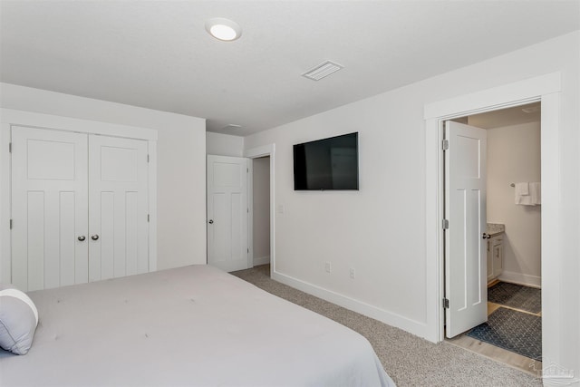 bedroom featuring connected bathroom, light carpet, visible vents, baseboards, and a closet