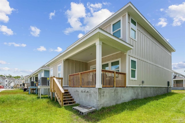 rear view of house with board and batten siding, a residential view, a yard, and stairway