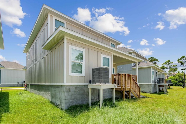 exterior space with board and batten siding, a lawn, and central air condition unit