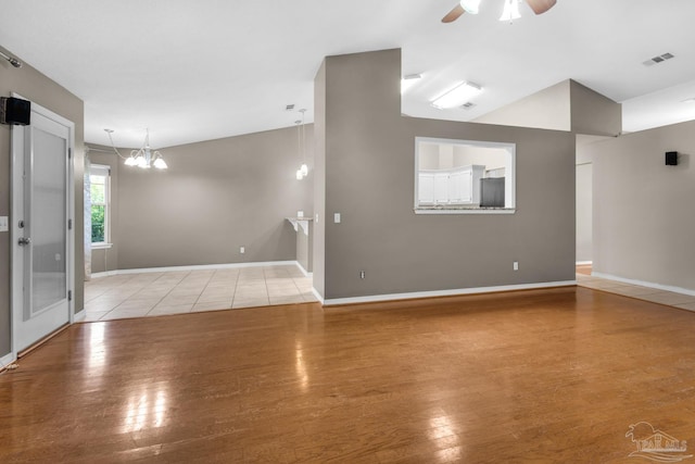 spare room with wood finished floors, ceiling fan with notable chandelier, baseboards, and visible vents