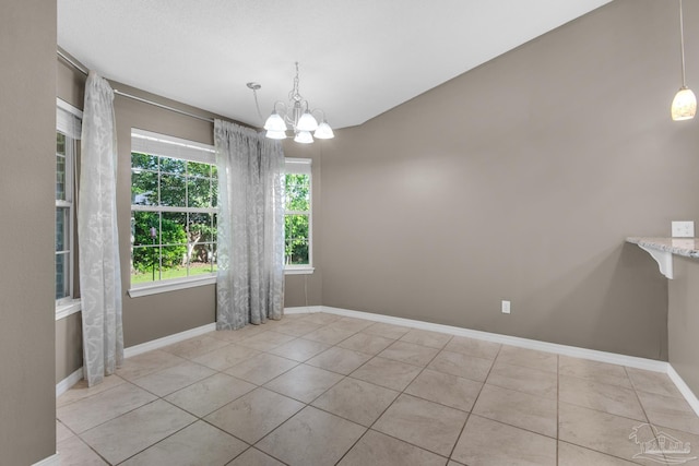 unfurnished dining area featuring tile patterned floors, a notable chandelier, and baseboards