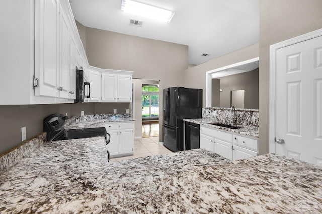 kitchen featuring light tile patterned floors, a sink, black appliances, white cabinetry, and light stone countertops