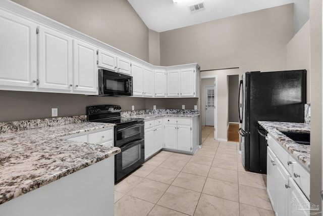 kitchen with light stone counters, visible vents, white cabinetry, and black appliances