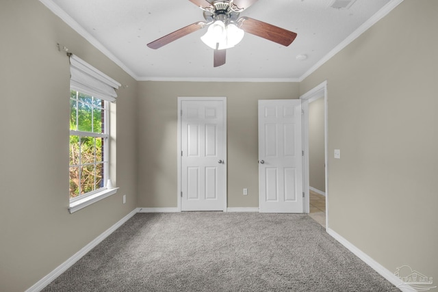 unfurnished bedroom featuring ceiling fan, carpet flooring, baseboards, and ornamental molding
