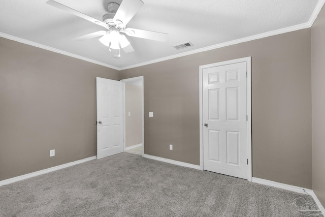 unfurnished bedroom featuring baseboards, ornamental molding, carpet floors, visible vents, and ceiling fan
