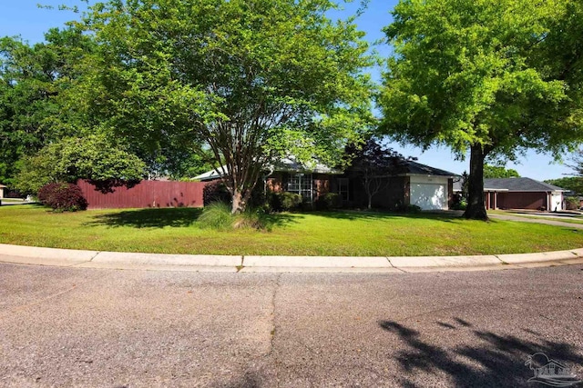 view of front facade featuring a front lawn, fence, and an attached garage