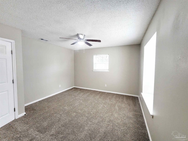 empty room with dark carpet, a textured ceiling, and ceiling fan