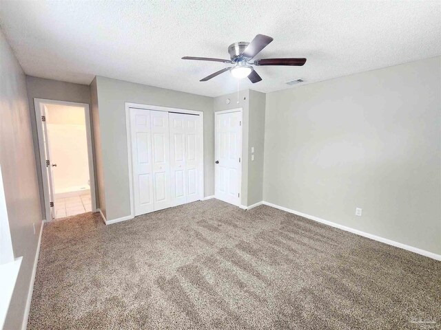 unfurnished bedroom with a closet, ceiling fan, a textured ceiling, and carpet floors