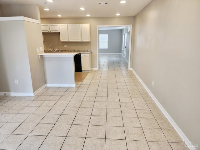 kitchen with black dishwasher, light tile patterned flooring, and white cabinets