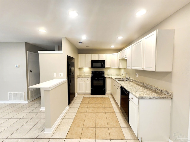 kitchen featuring sink, light stone countertops, black appliances, light tile patterned floors, and white cabinetry