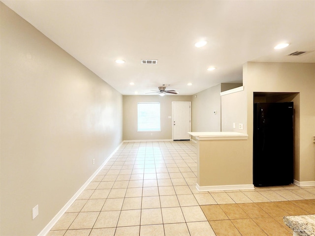 kitchen featuring ceiling fan, light tile patterned floors, and black fridge