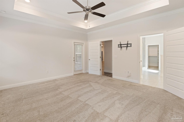 spare room featuring ornamental molding, light colored carpet, and a tray ceiling