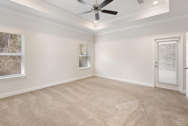 carpeted spare room with a tray ceiling, ornamental molding, and ceiling fan