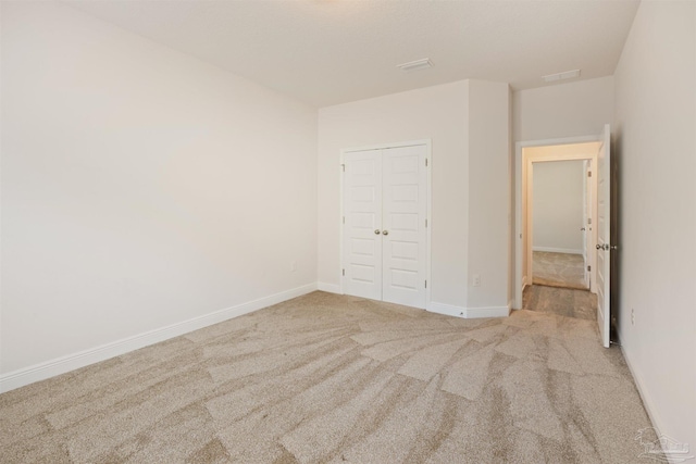 unfurnished bedroom featuring light colored carpet and a closet