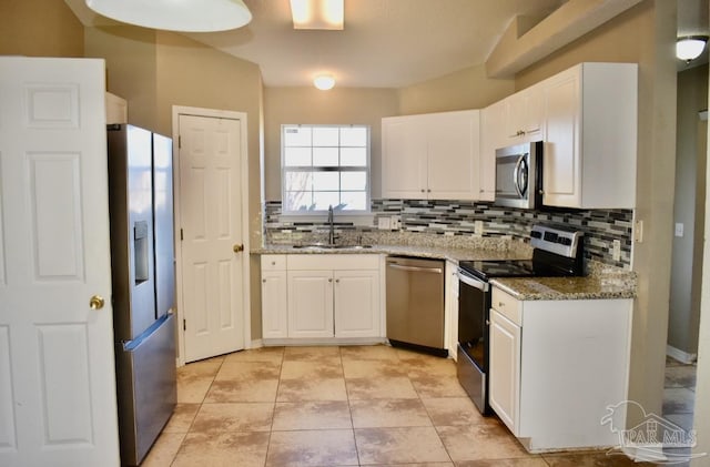 kitchen featuring appliances with stainless steel finishes, white cabinetry, light stone counters, and sink