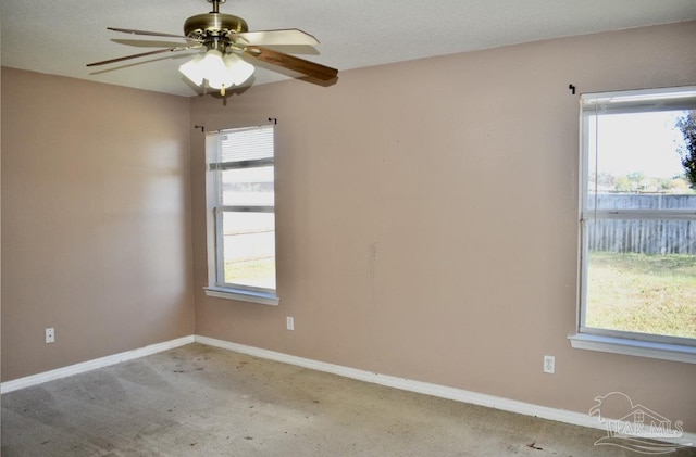 carpeted empty room with a wealth of natural light, ceiling fan, and a textured ceiling