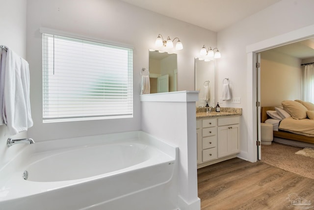 bathroom with hardwood / wood-style flooring, vanity, and a bathing tub