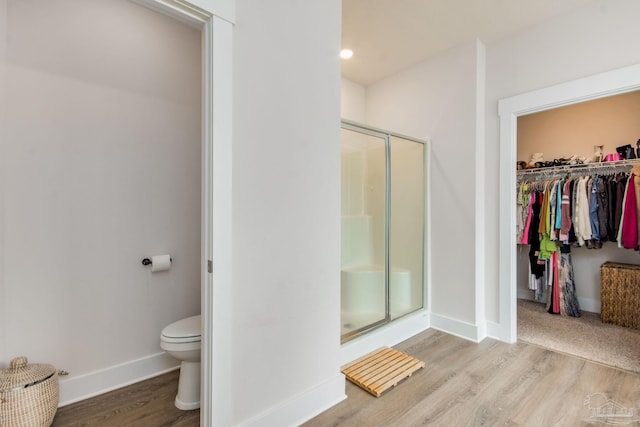 bathroom featuring walk in shower, toilet, and hardwood / wood-style flooring