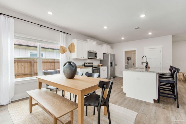 dining space with light hardwood / wood-style flooring and sink