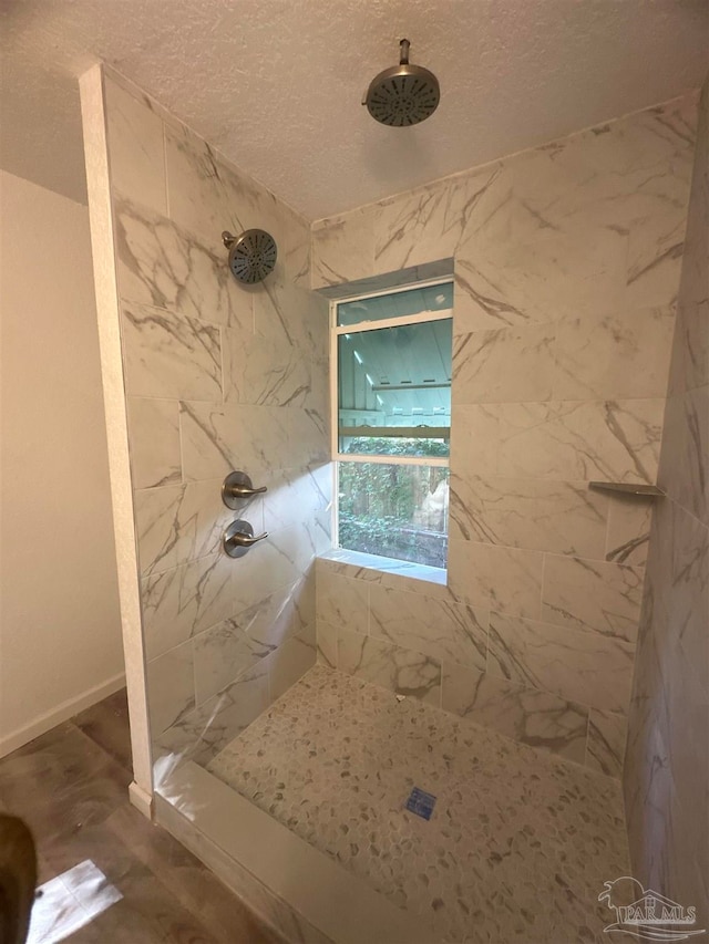 bathroom with a textured ceiling and a tile shower