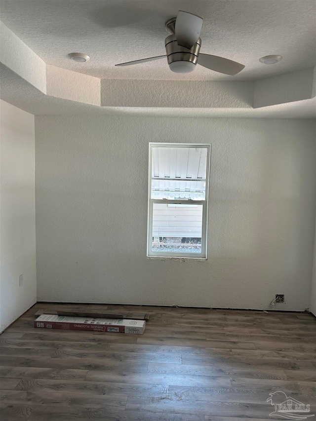 spare room featuring a raised ceiling, dark hardwood / wood-style floors, and ceiling fan