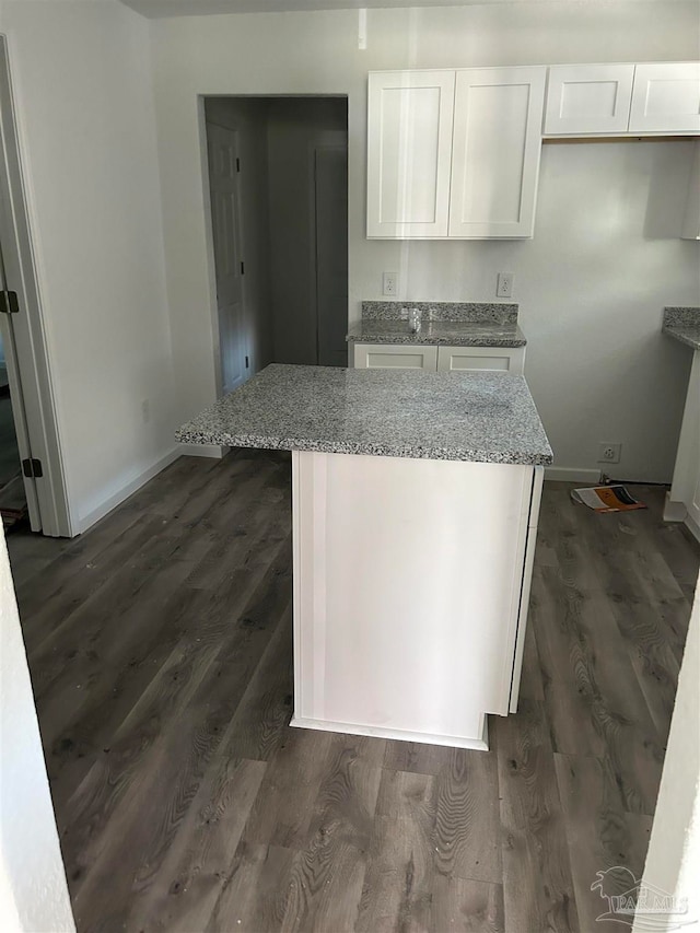 kitchen with white cabinets, light stone countertops, and dark wood-type flooring