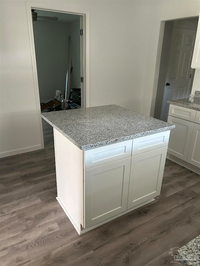 kitchen featuring light stone counters, white cabinets, and dark wood-type flooring