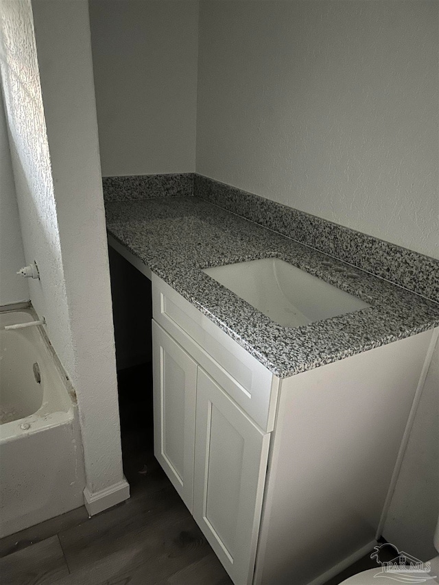 bathroom with wood-type flooring, vanity, and a tub to relax in