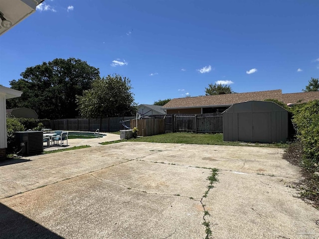 view of patio featuring central AC unit, an outbuilding, a shed, and a fenced backyard