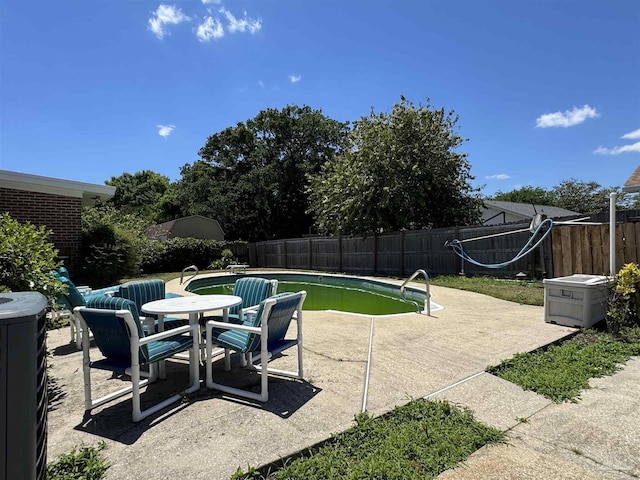 view of pool featuring a fenced backyard, a fenced in pool, a patio area, and central air condition unit