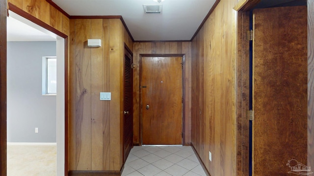 hall featuring visible vents, crown molding, wood walls, baseboards, and light tile patterned flooring