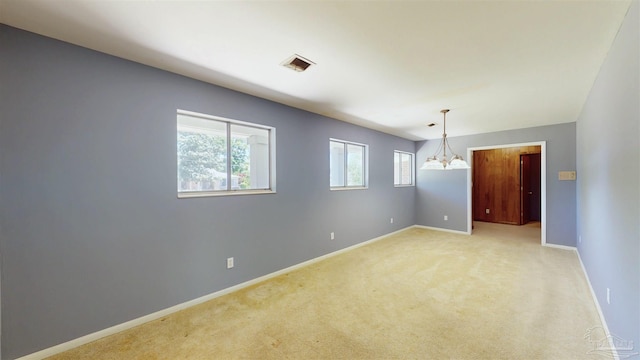 empty room with a chandelier, baseboards, visible vents, and light carpet