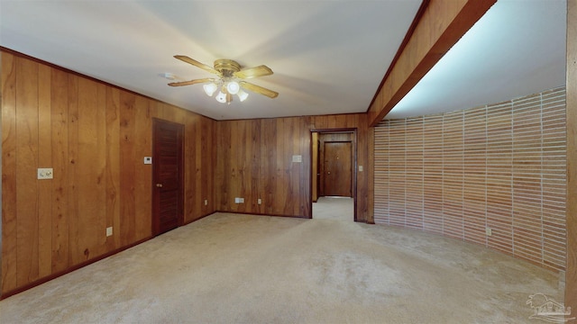 carpeted spare room with wooden walls and a ceiling fan