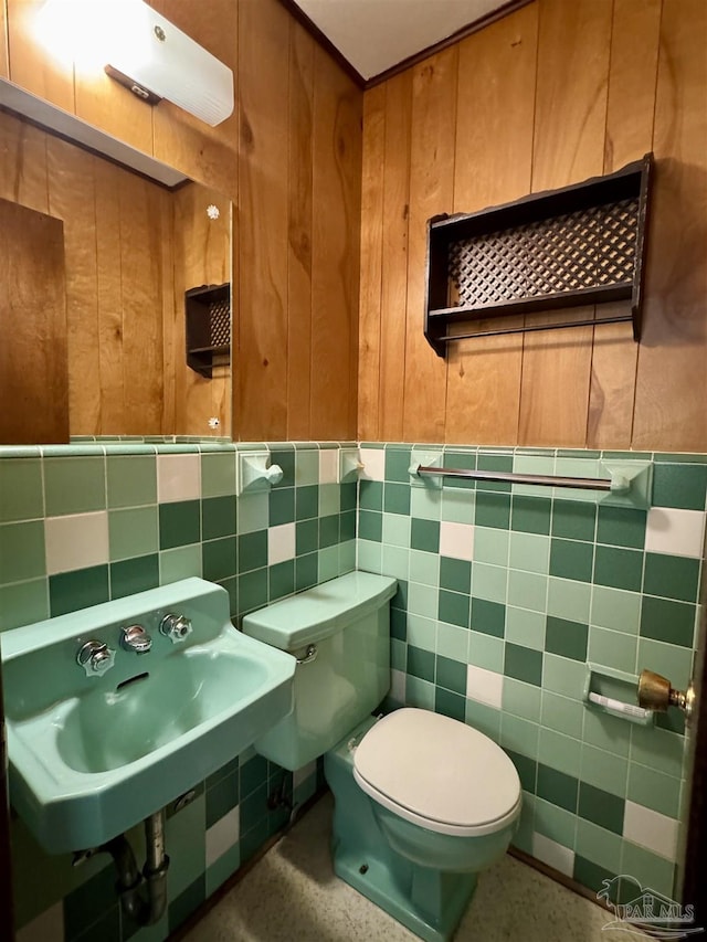 bathroom with wooden walls, tile walls, toilet, and a sink