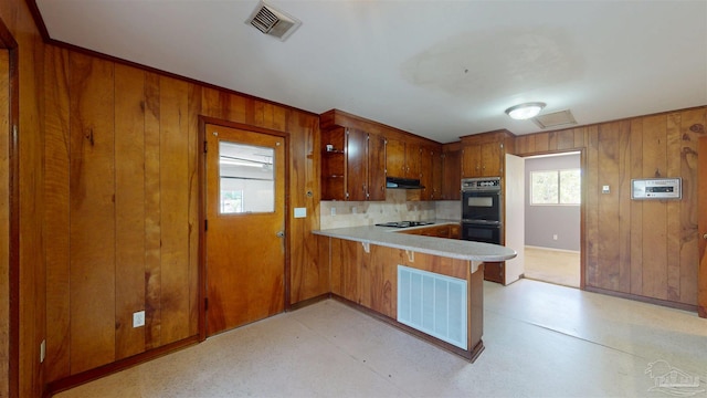 kitchen with dobule oven black, under cabinet range hood, a peninsula, and visible vents