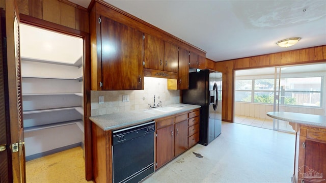 kitchen featuring tasteful backsplash, a sink, light countertops, black appliances, and light floors