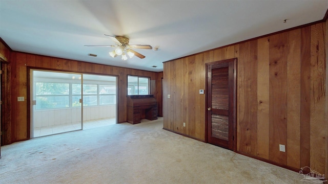 interior space featuring visible vents, carpet flooring, ceiling fan, and wooden walls