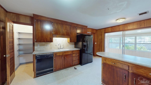 kitchen with tasteful backsplash, a sink, light countertops, black appliances, and light floors