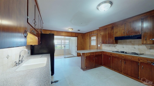 kitchen featuring a peninsula, light countertops, under cabinet range hood, a sink, and black appliances