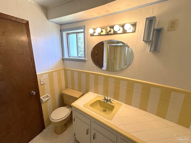 bathroom with vanity, tile patterned floors, toilet, and tile walls